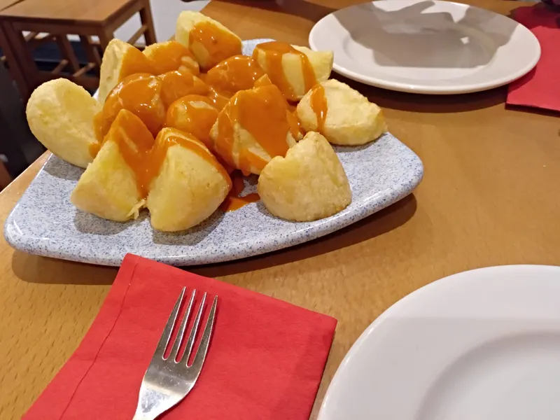 Ración de patatas bravas con servilleta roja