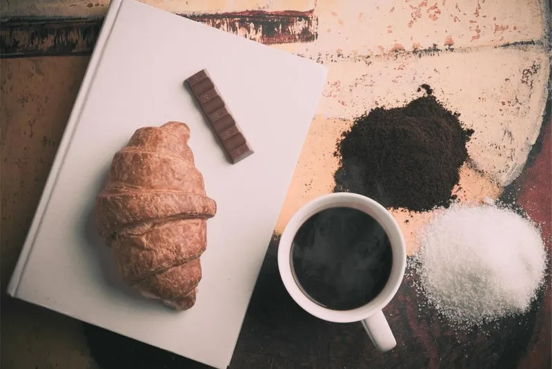 Taza de café solo y un cruasán sobre una mesa de madera