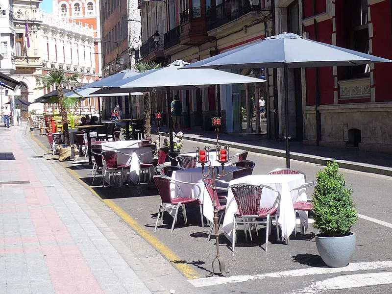 Terraza de bar con mesas y sombrillas en una calle peatonal