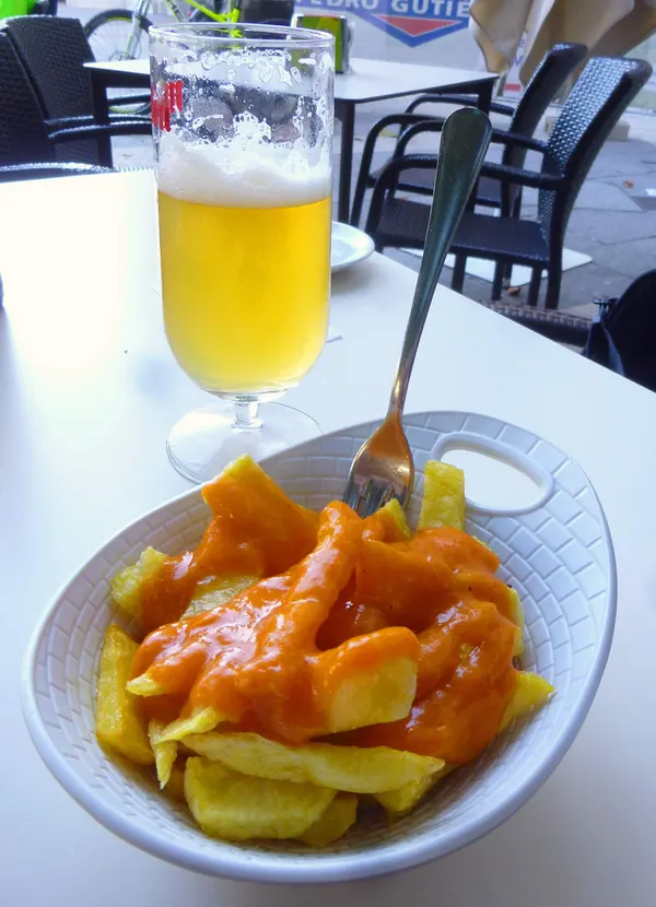 Caña y patatas bravas en una mesa de terraza