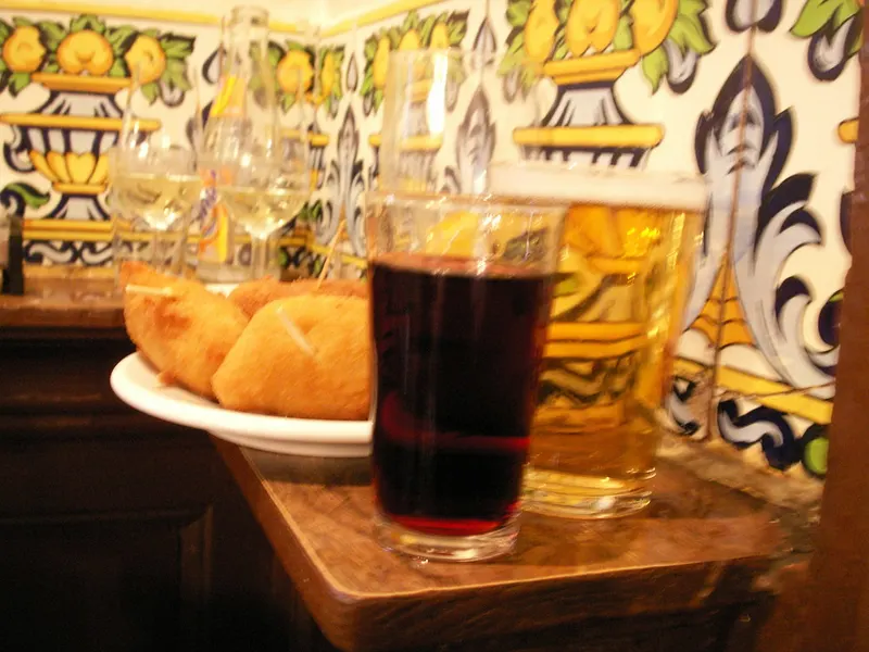 Vermut, caña y empanadillas en la barra de un bar con azulejos